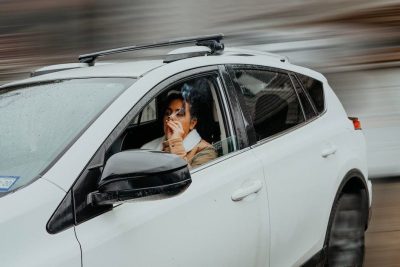 A woman in a car, examining paperwork, emphasizing the concept of Auto insurance premiums.