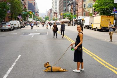 Woman walking her dog on a leash in the middle of the road.